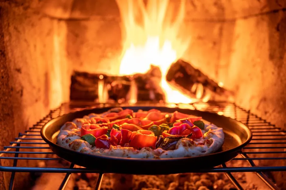 Freshly prepared pizza baking in a wood-fired oven with vibrant toppings and a crispy crust.